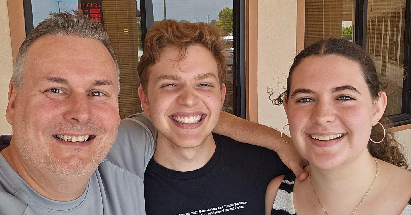 Mr. Robin Ryon smiling with two students